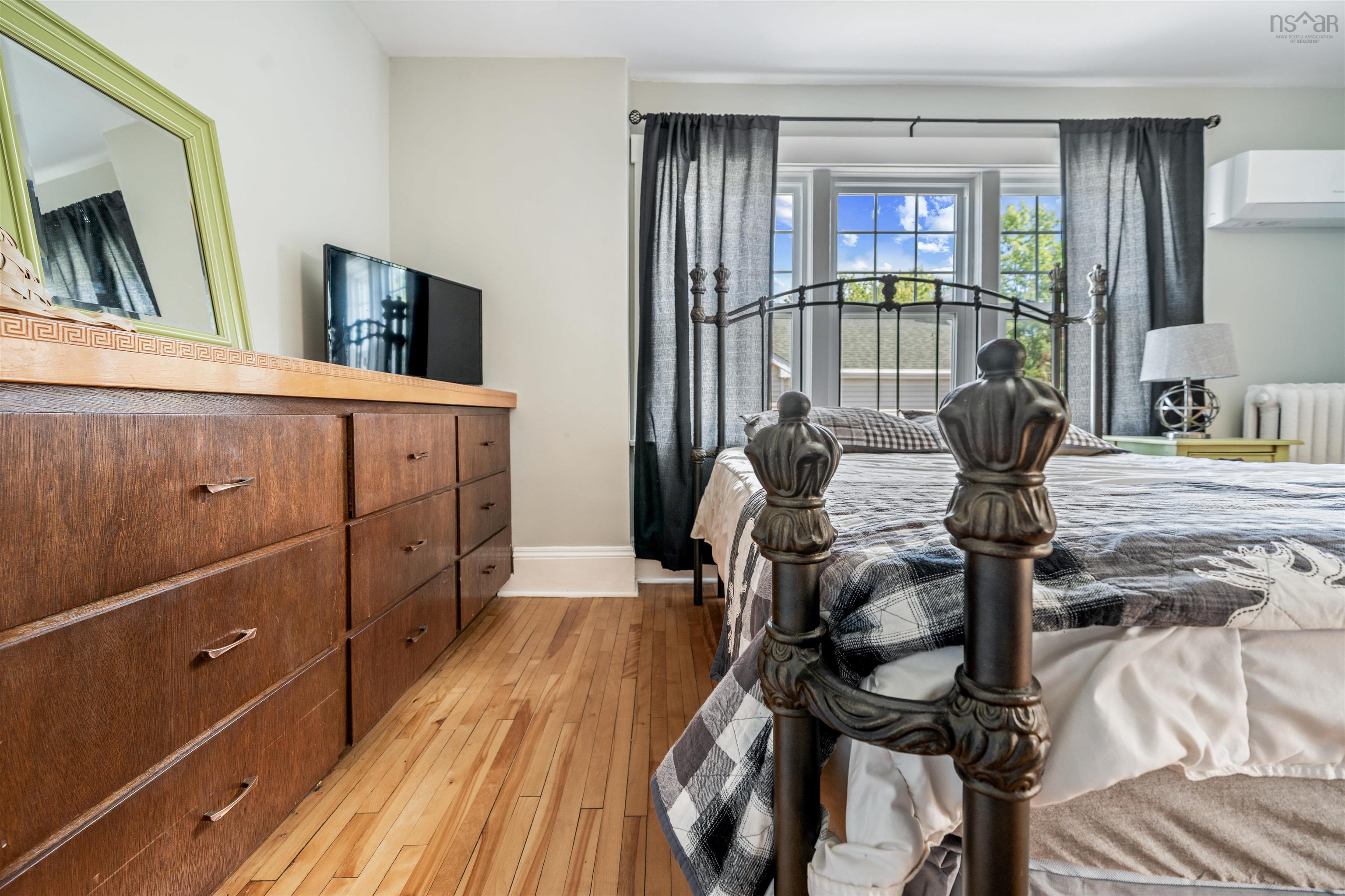 Bedroom with light wood finished floors, radiator, and a wall unit AC