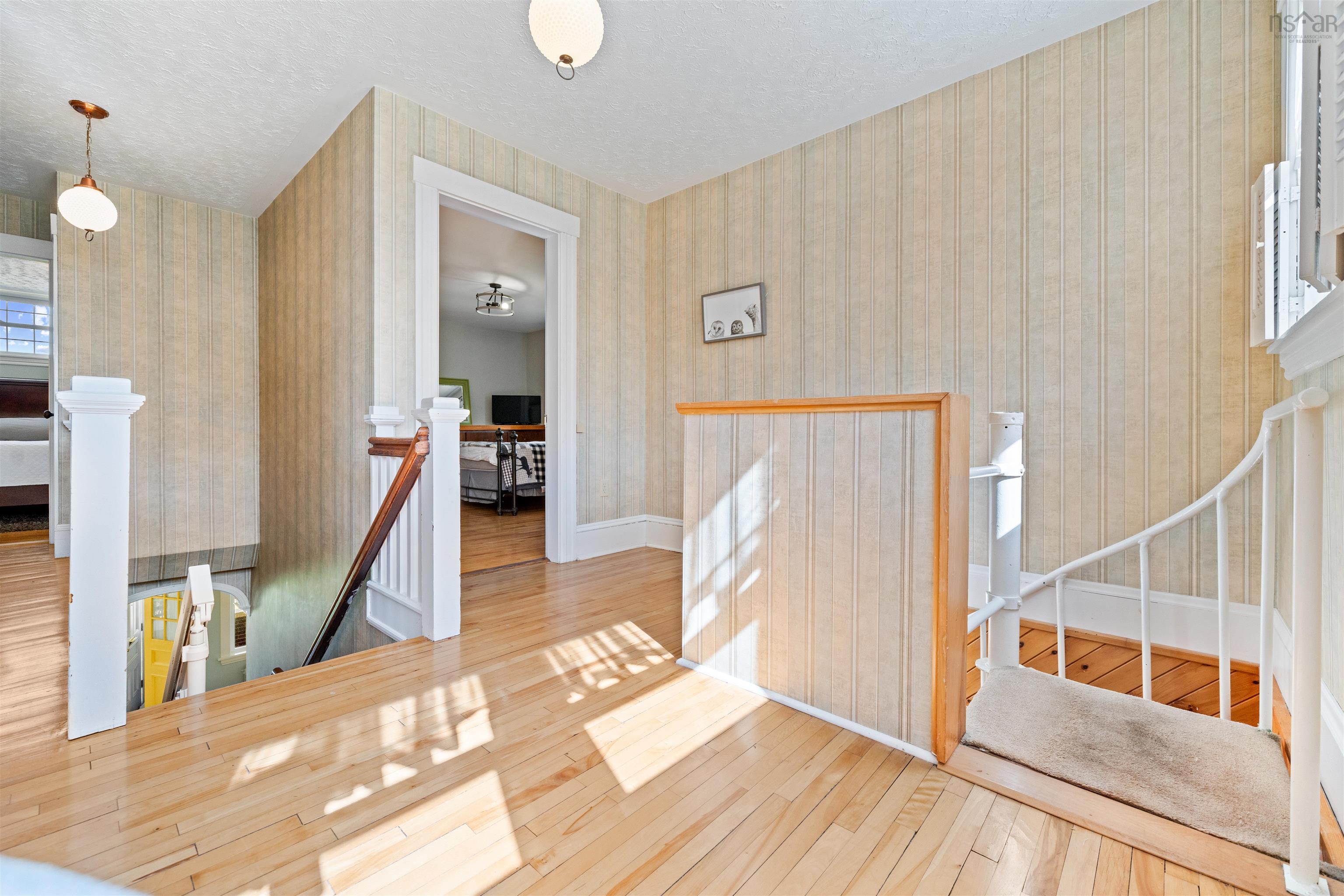 Corridor with an upstairs landing, stairway, hardwood / wood-style flooring, a textured ceiling, and wallpapered walls