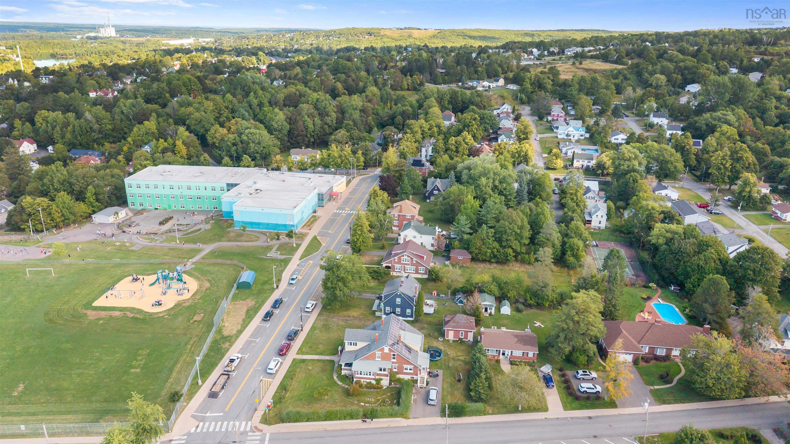 Aerial view of property's location with nearby suburban area and a tree filled landscape