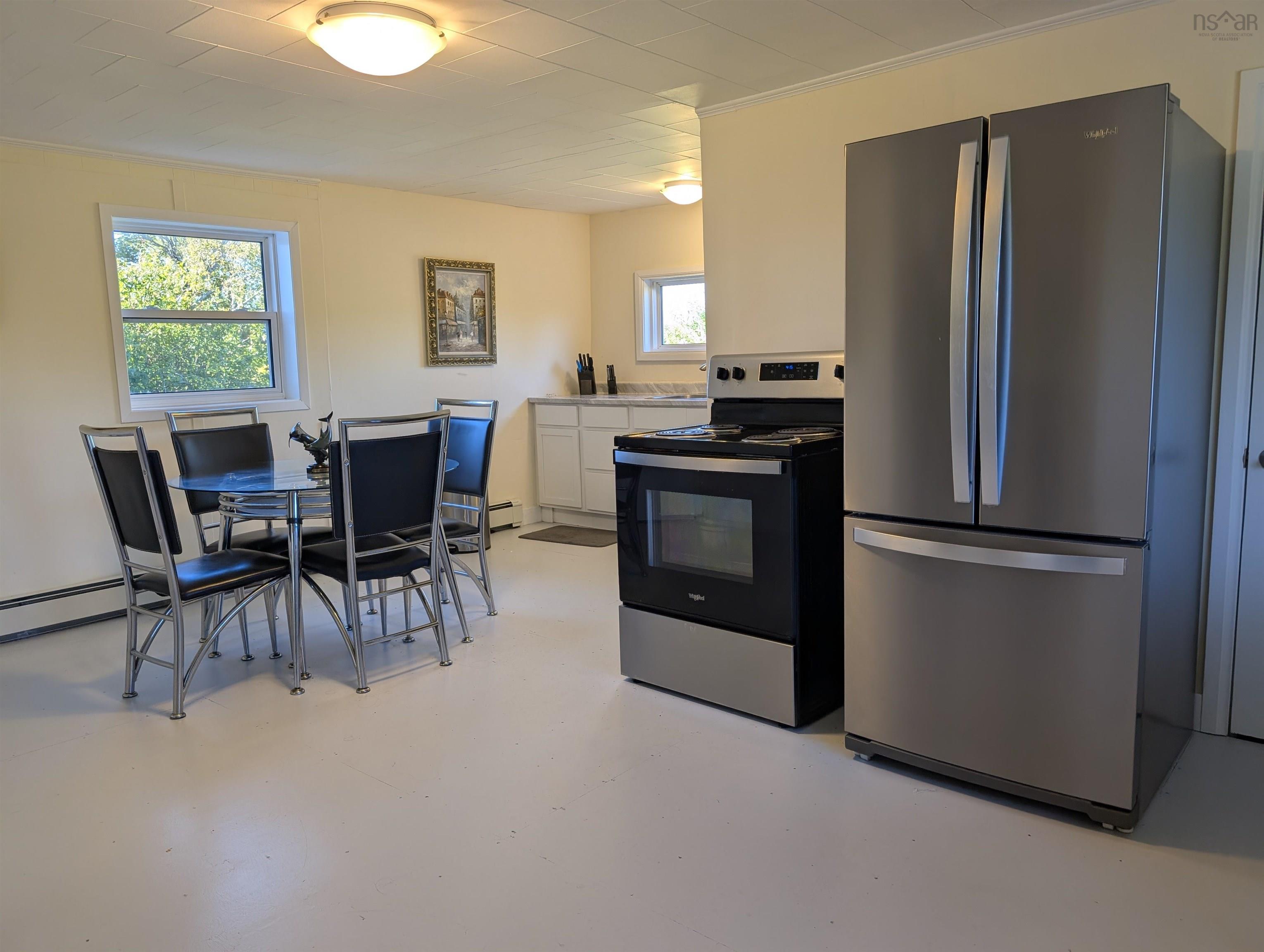 Kitchen with appliances with stainless steel finishes, white cabinetry, concrete floors, light countertops, and crown molding