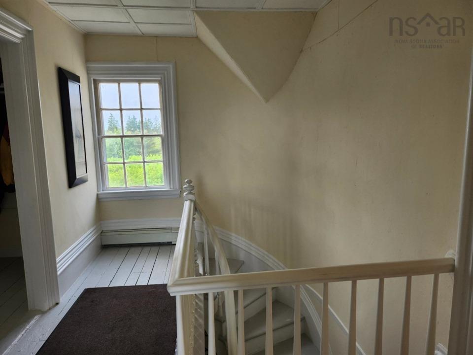 Staircase featuring a baseboard radiator, a paneled ceiling, and wood finished floors