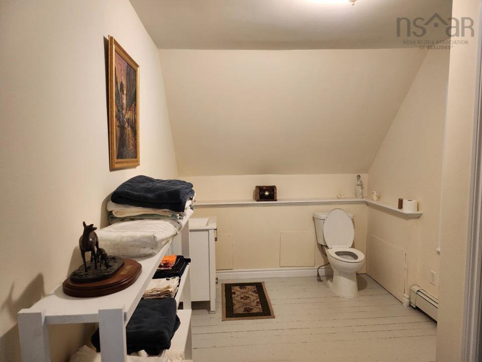 Half bathroom with vaulted ceiling, a baseboard radiator, and light wood-style flooring