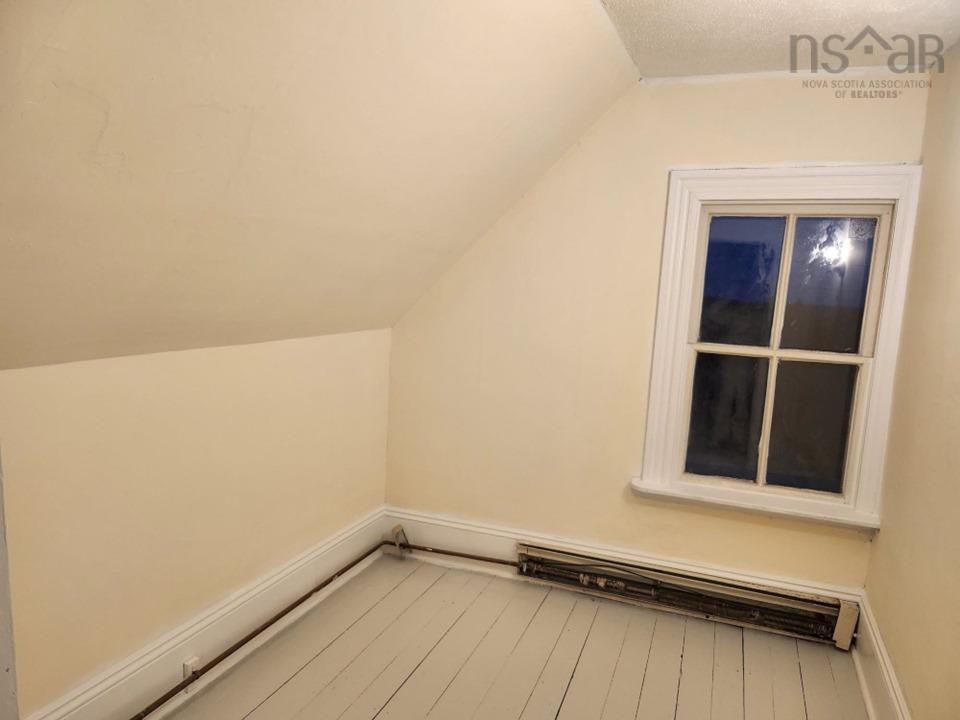Bonus room with lofted ceiling, a baseboard heating unit, wood finished floors, and a textured ceiling