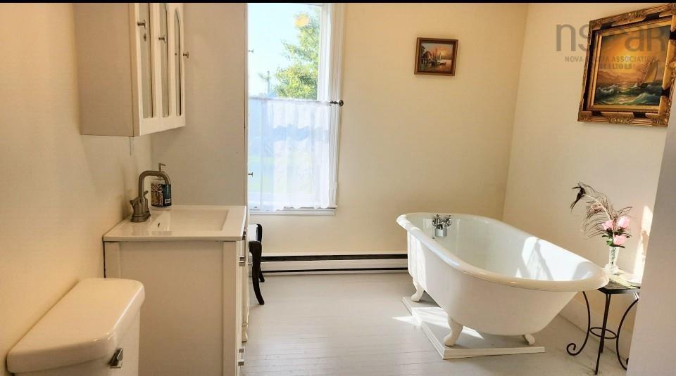 Full bath featuring a freestanding tub, vanity, healthy amount of natural light, and a baseboard heating unit
